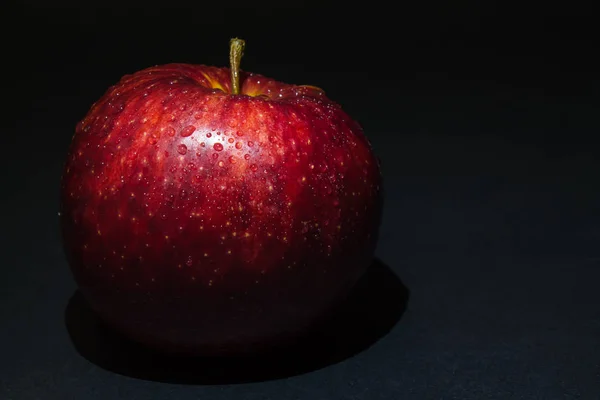 Rode appel met druppels dauw op een zwarte achtergrond — Stockfoto