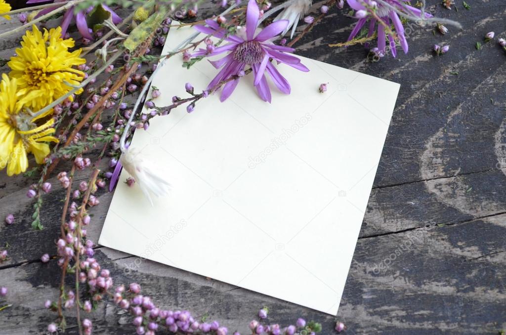 Various summer wild flowers on textured old wooden background with place for text. Top view.