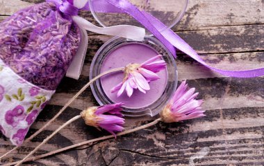 Mor göz farı, çiçekler ve lavanta karanlık dokulu ahşap arka plan üzerinde bir paket çevrili. Moda ve makyaj Tema