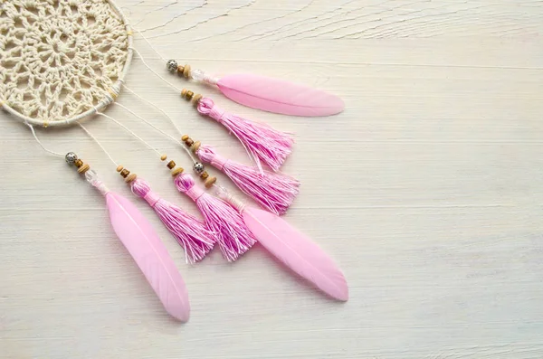 Dreamcatcher ahşap arka plan üzerinde pembe tüylü. Etnik tasarım, boho tarzı, kabile simgesi.