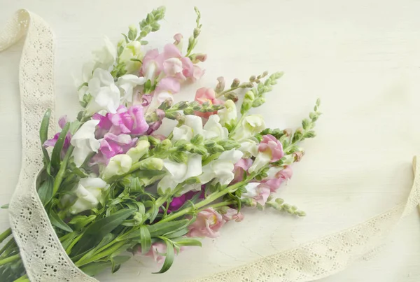 Antirrinum su fondo bianco in legno. Laccio in cotone vintage in stile bocho — Foto Stock