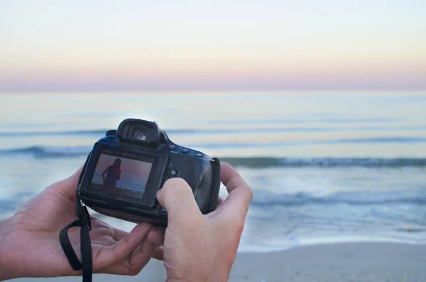 Rękach fotografa, trzymając aparat fotograficzny z obrazem w morzu — Zdjęcie stockowe
