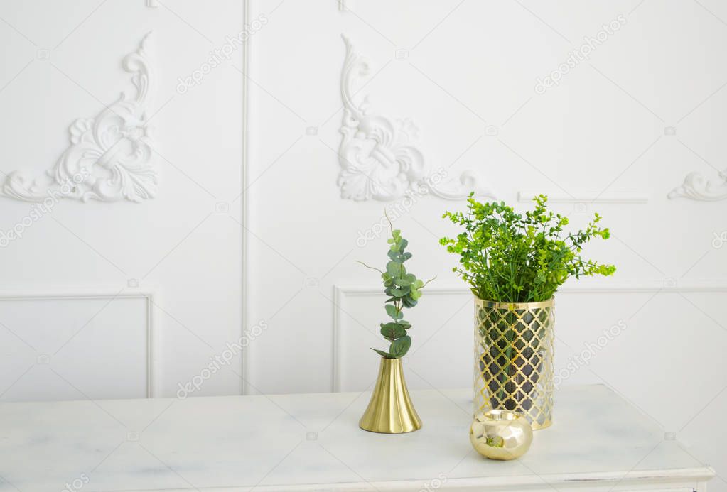 Brass golden candlestick. Green decorative plants in brass vase.