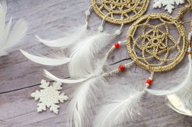 Dreamcatcher ahşap arka plan üzerinde tüyleri ile. Etnik tasarım, boho tarzı, kabile simgesi. Eski ahşap antika arka plan üzerinde beyaz Noel ve yeni yıl kar tanesi.