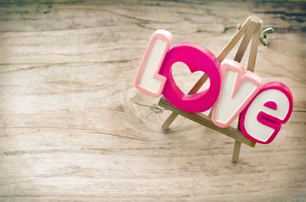 Decorative inscription Love on a small wooden easel that stands in vintage board — Stock Photo, Image