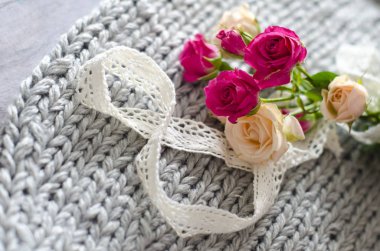 Bir buket gül ihale Merinos yün ve ahşap gri bir arka plan üzerinde. Şekil 8 pamuk doğal dantel yapılır. 8 Mart tarafindan fotograf.