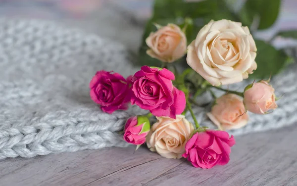 Un ramo de rosas sobre un fondo gris de tierna lana de merino y madera — Foto de Stock