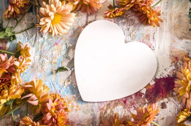 Beyaz kalp turuncu kasımpatılarla çevrili..