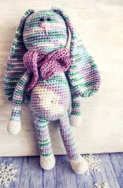 Kar taneleri ve el fenerleri arasında pastel renkli örülmüş bir tavşan. .