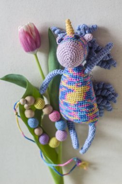 Lale ve örülmüş boncuklu tek boynuzlu at. Güzel el yapımı oyuncak. Bahar fotoğrafı.