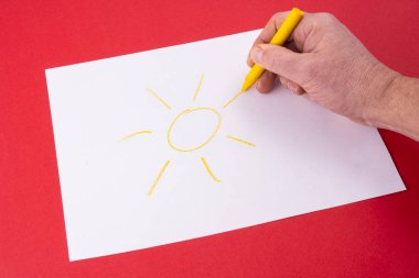 bir mum boya kalemi ile beyaz kağıt üzerine çizilmiş bir güneş