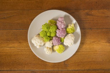 Beyaz, pembe ve yeşil karnabahar ahşap bir masa üzerinde bir plaka üzerinde