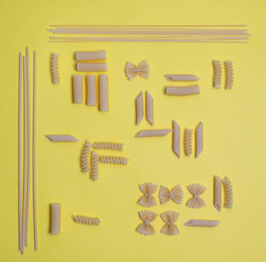 Renkli bir yüzeye yerleştirilmiş bazı makarna türlerinin üst görünümü