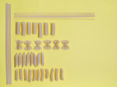 Renkli bir yüzeye yerleştirilmiş bazı makarna türlerinin üst görünümü