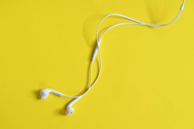 Sarı bir yüzeyde bir çift kulaklık.