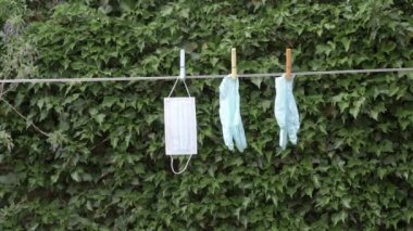 Bir koruyucu maske ve bahçede asılı bir çift eldiven.