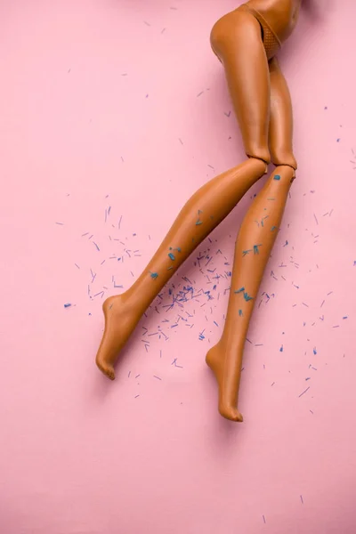 Πόδια Μιας Πλαστικής Κούκλας Μαλλιά Σκορπισμένα Μαλακό Ροζ Φόντο — Φωτογραφία Αρχείου