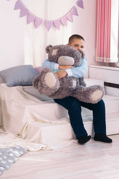 cute little caucasian boy hugs big gray teddy bear