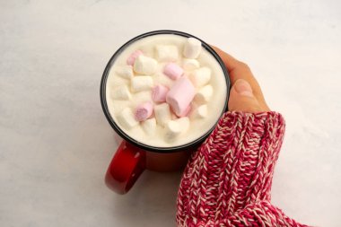 Kadın eli kırmızı örgü süveter içinde, elinde lokumlu sıcak bir içecek tutuyor.