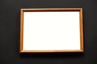 Siyah duvarda boş bir alan asılı ahşap fotoğraf çerçevesi.