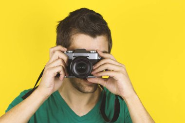 Yong yakışıklı adam sarı arka planda izole fotoğraf mağarası tutuyor.