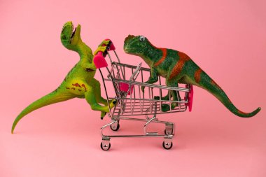 Dinozorların birbirini pembe arka planda alışveriş arabalarında yuvarladığı komik bir kartpostal.