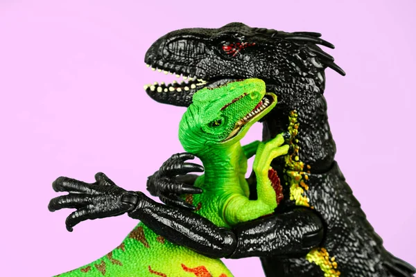 两只塑料恐龙抱在一起 彼此隔离在粉红色的背景下 — 图库照片