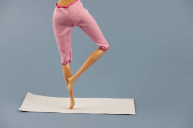 Yogadaki plastik bebek gri arka planda poz veriyor, sağlıklı yaşam tarzı konsepti