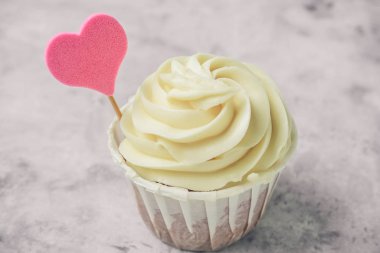 Gri beton bir masada pembe kalpli kapkeki kapat.