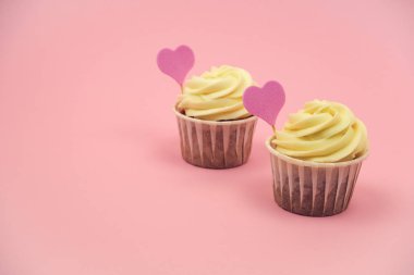 Pastel pembe arka planda pembe kalpli, fotokopi alanı olan iki kek.