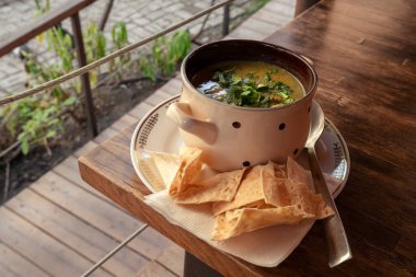 Polka noktasını kapat. Bir tabak kremalı çorba ve maydanozlu. Tahta bir masanın üzerinde, restoranda pita cipsi ile servis ediliyor.