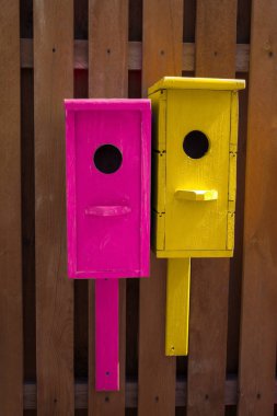 Tahta bir çitin üzerinde parlak, eski, ahşap kuş evleri.