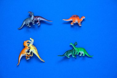 Üst manzara küçük plastik dinozorlar çiftler ve mavi arka planda yalnız bir dinozor.