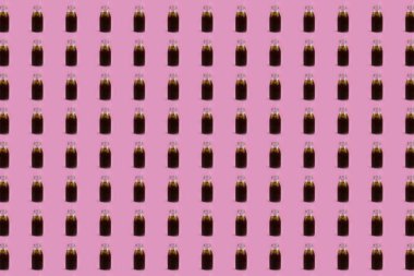 Pembe arka planda plastik tüp desenli soğuk soda şişesi.