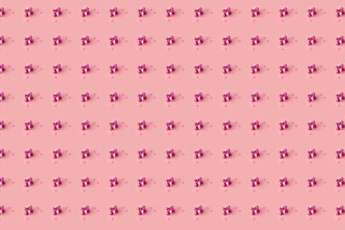 Yaratıcı desenli küçük hediye kutuları pembe saten fiyonklarla süslenmiş ve pembe kalpler pastel arka planda.