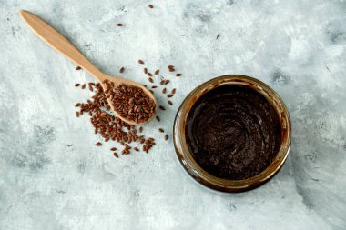 Üstünde keten tohumu ezilmiş cam kavanoz beton bir masada keten tohumlu tahta kaşık, vegan çiğ süper yiyecekler.