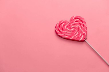 Tatlı kalp şekilli lolipop pembe arka planda fotokopi alanı, yukarıdan görünüm