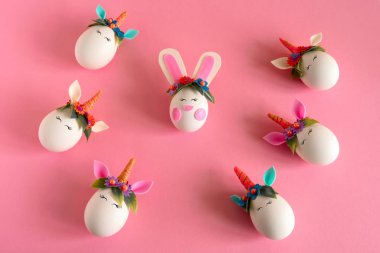 Üst manzara düz paskalya yumurtaları tek boynuzlu atlar ve pastel pembe arka planda bir tavşan.