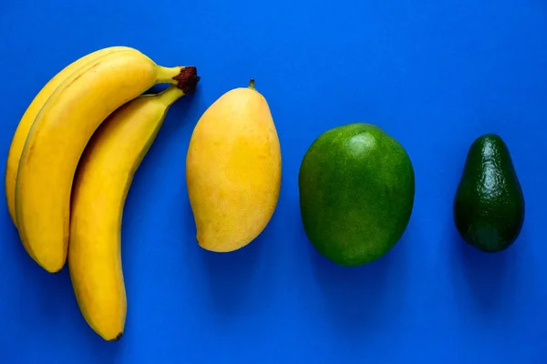 青い背景に新鮮なバナナ マンゴー アボカドのトップビューのレイアウト — ストック写真