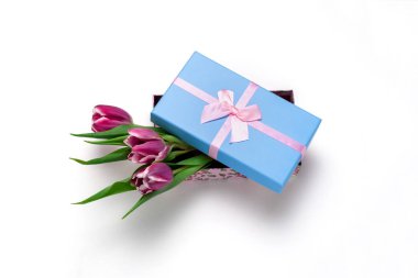 Üst manzara pembe laleler mavi bir kutuda pembe saten kurdele ile beyaz arka planda izole edilmiş.