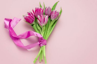 Üst manzara düz pembe laleler, ipek kurdeleli yumuşak pembe arka plan, fotokopi alanı, bahar tatili kartı konsepti.