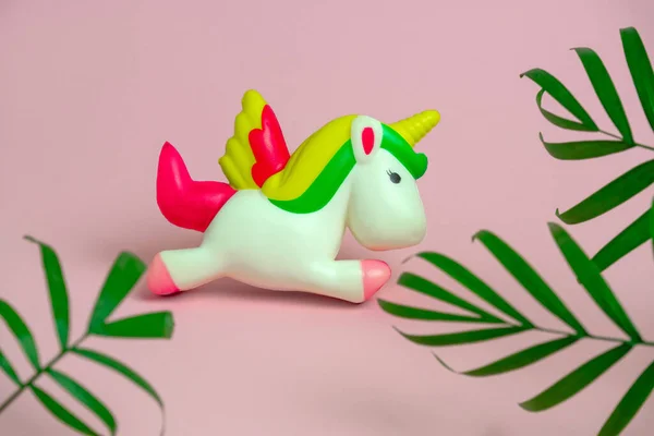 Niedliches Antistress Einhorn Spielzeug Und Grüne Tropische Palmenblätter Auf Pastellrosa — Stockfoto