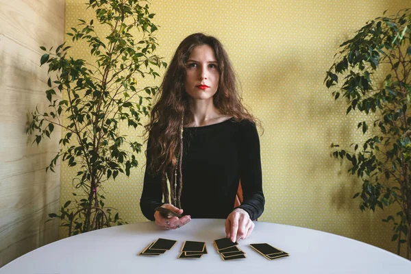Siyah kadife elbiseli kadın masaya kartlarını seriyor.