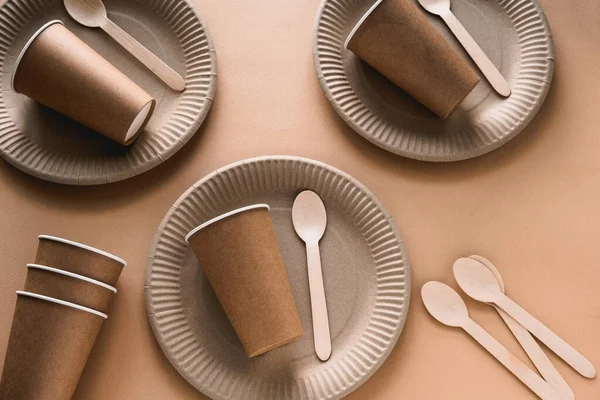 disposable paper and wood biodegradable tableware on a beige background, eco friendly lifestyle concept