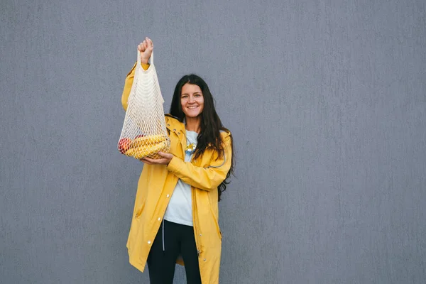 Красива Щаслива Молода Жінка Жовтому Плащі Тримає Сумку Свіжими Бананами — стокове фото