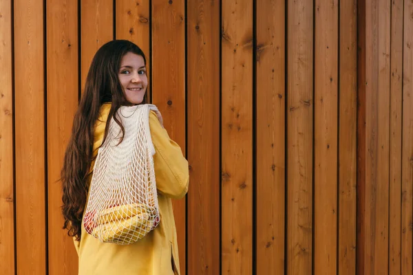 Joven Feliz Mujer Sosteniendo Red Bolsa Compras Calle Contra Pared — Foto de Stock