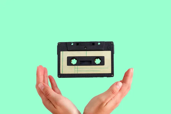 vintage audio tape flying into female hands on a green background