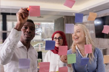 İş takım fikirler cam duvar yapışkan not ile tartışıyor