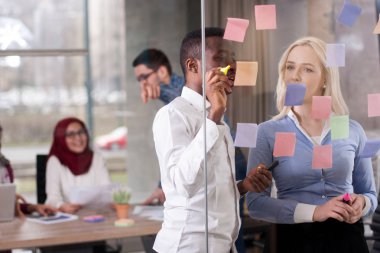 İş iş arkadaşları fikirler cam duvar ile yapışkan kontrol ediyor