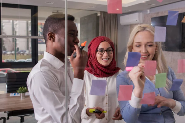 Business team is discussing ideas on glass wall with sticky note — Stock Photo, Image